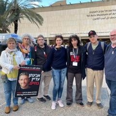 Group of people in Tel Aviv Hostage square looking serious holding photo of missing person