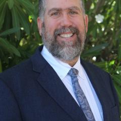 Smiling man with goatee in blue suite with white shirt