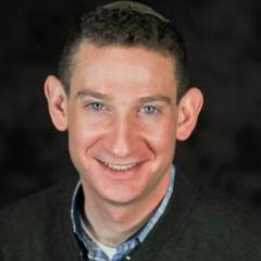 Smiling man in a blue sweater wearing a kippah