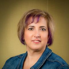 Rachel Roth headshot. smiling and wearing a jean jacket. Medium brown hair and brown eyes