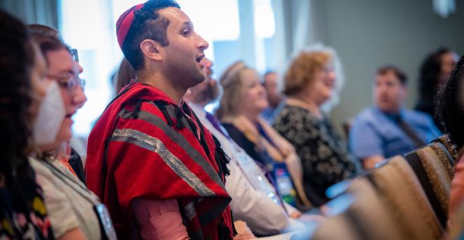 Cantors and musicians singing at shacharit. Cantor in red tallit and kippah standing in foreground