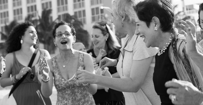 Group of women singing and clapping on the beach