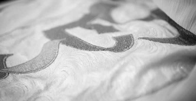 Black and white photo of white High Holy Day Torah Mantel (covering) with silver embroidered lettering