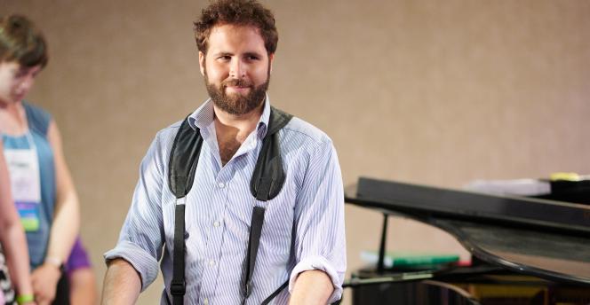 Cantor Tobias Glazer playing a drum hanging from his neck