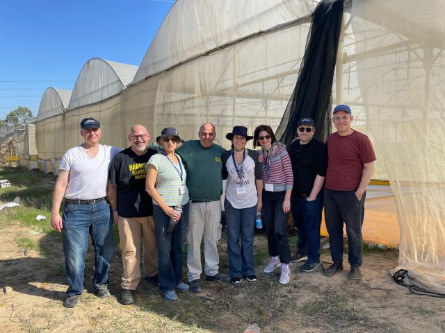 Group of 8 people standing outside of a greenhouse