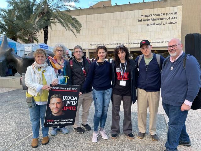 Group of people in Tel Aviv Hostage square looking serious holding photo of missing person