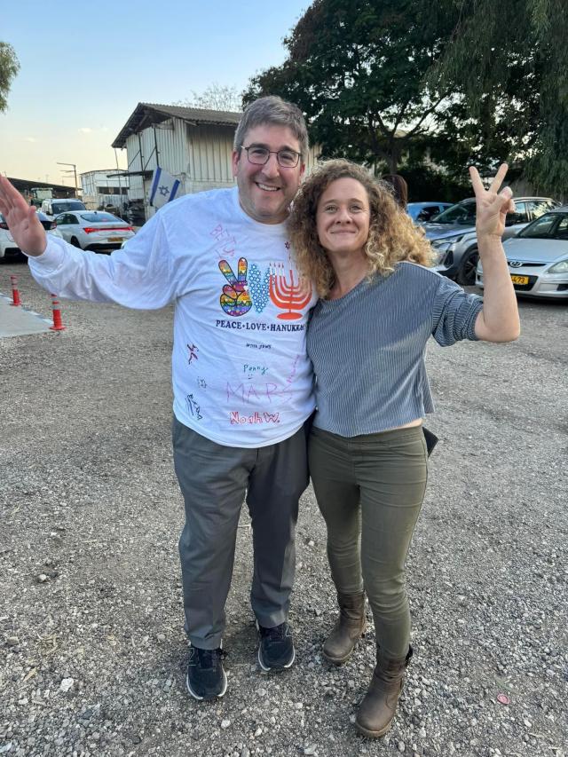 Man and woman smiling at camera making peace signs