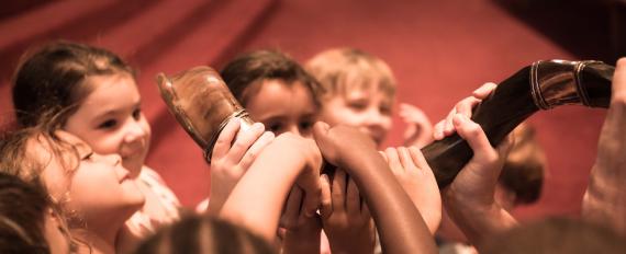 Children's hands grasping a shofar